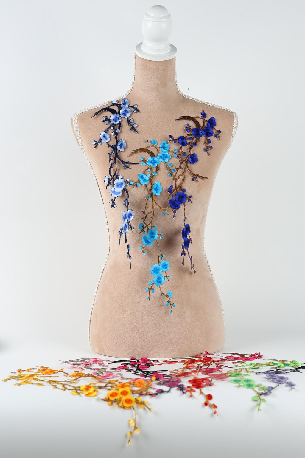 a mannequin with a floral design on its torso, including blue and purple flowers and branches.
