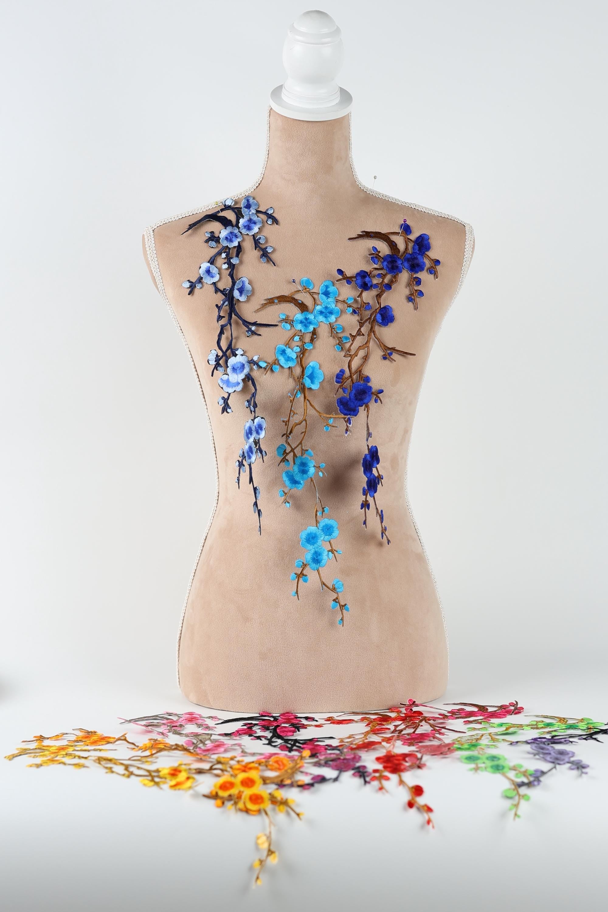 a mannequin with a floral design on its torso, including blue and purple flowers and branches.