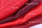 four different red fabric swatches, each with a label indicating the color and the fabric type.