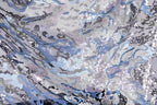 The image is a close-up view of a fabric with a complex, abstract pattern of sequins in various shades of blue, gray, and white. The pattern appears to be a mix of organic and geometric shapes, creating a visually striking and intricate design.
