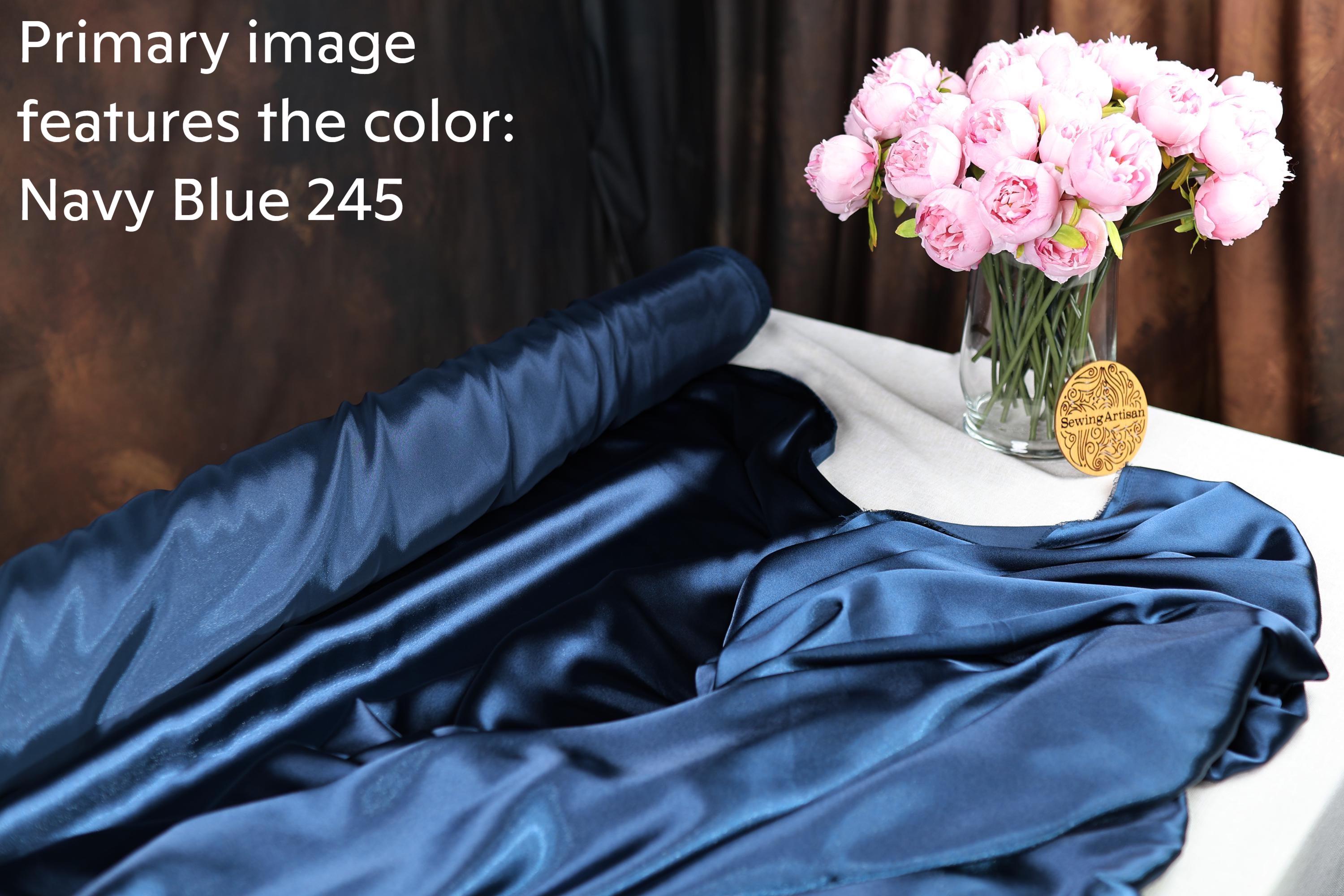 a navy blue fabric with a vase of pink flowers on a table, and there is a gold medal with text on the table.