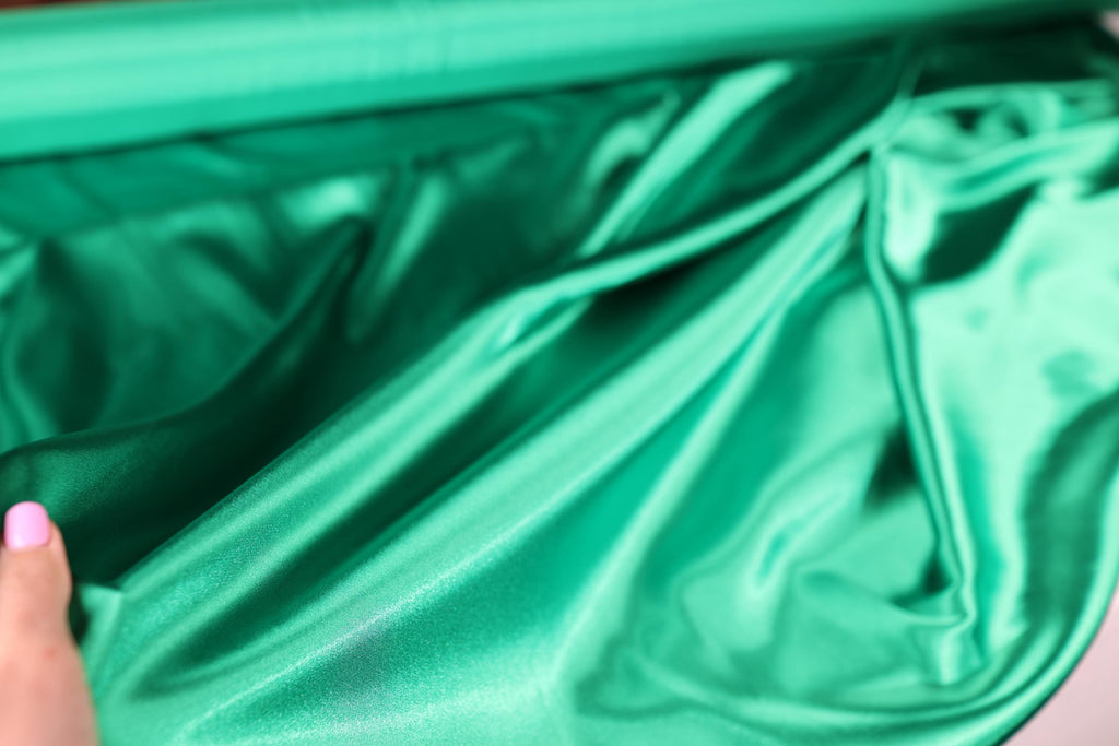 a woman&#39;s hand is holding a green piece of cloth