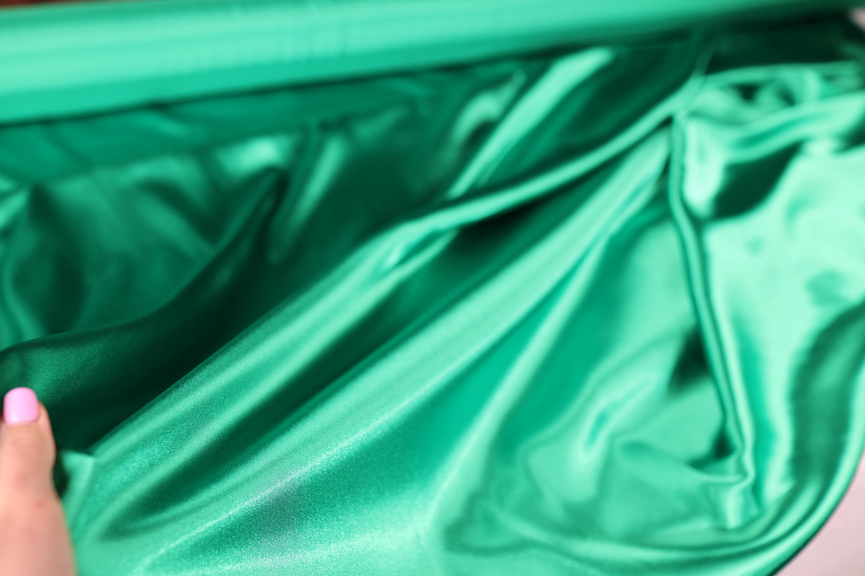 a woman&#39;s hand is holding a green piece of cloth