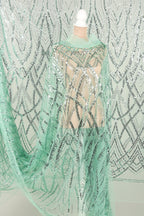 A mannequin wearing a green sequined dress with a patterned design.