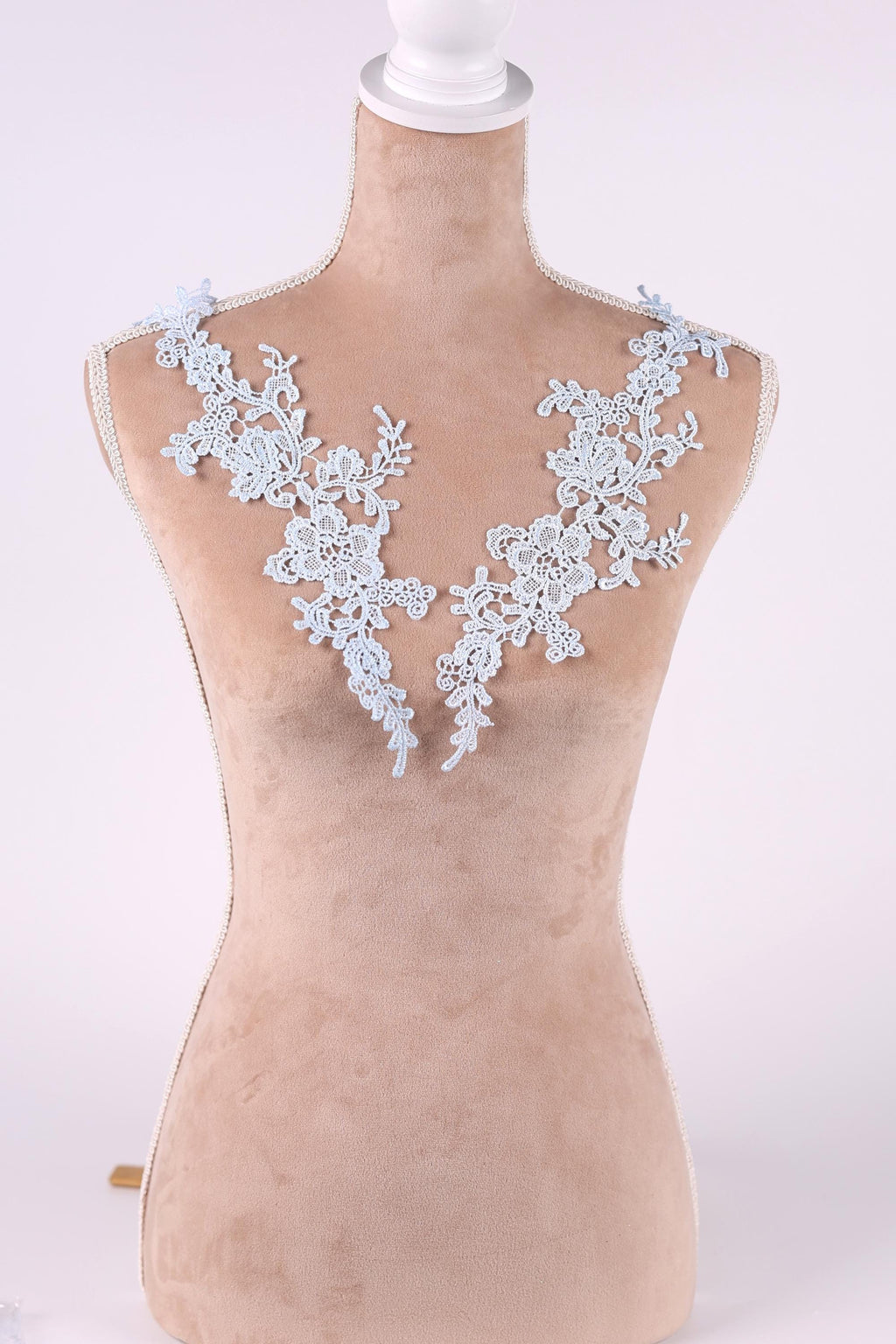 A mannequin wearing a white lace dress with delicate floral patterns on the shoulders.