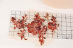 a clear ruler with red sequin flower-shaped pieces placed on it, indicating a sewing or crafting project.