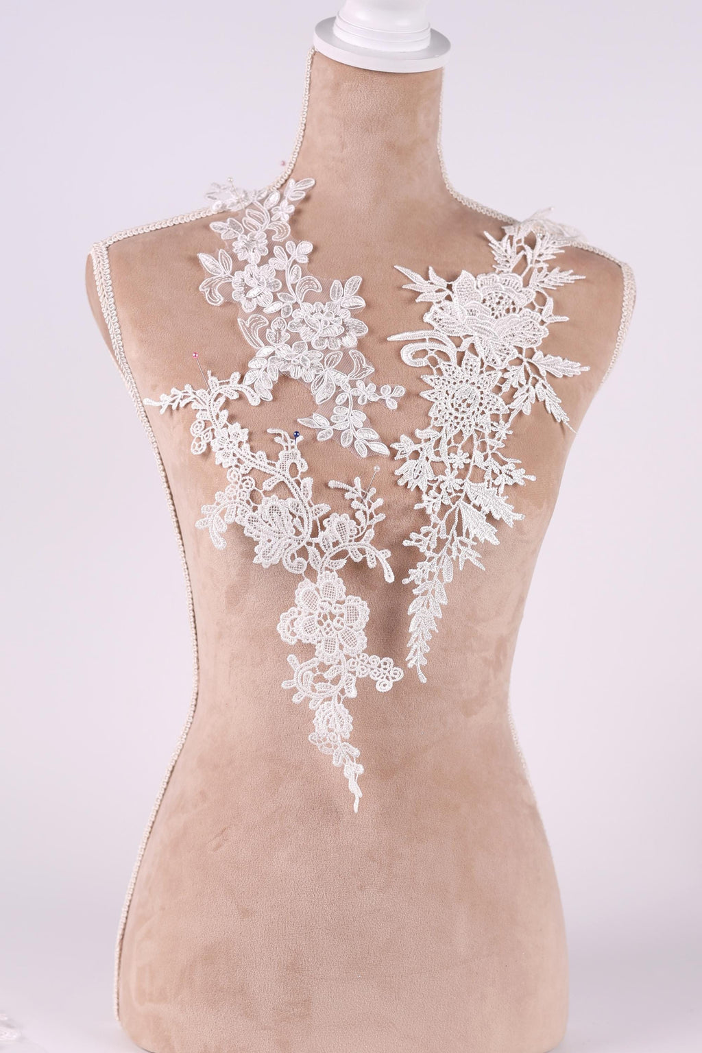A mannequin wearing a white lace dress with intricate floral patterns.