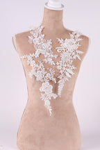 A mannequin wearing a white lace dress with intricate floral patterns.