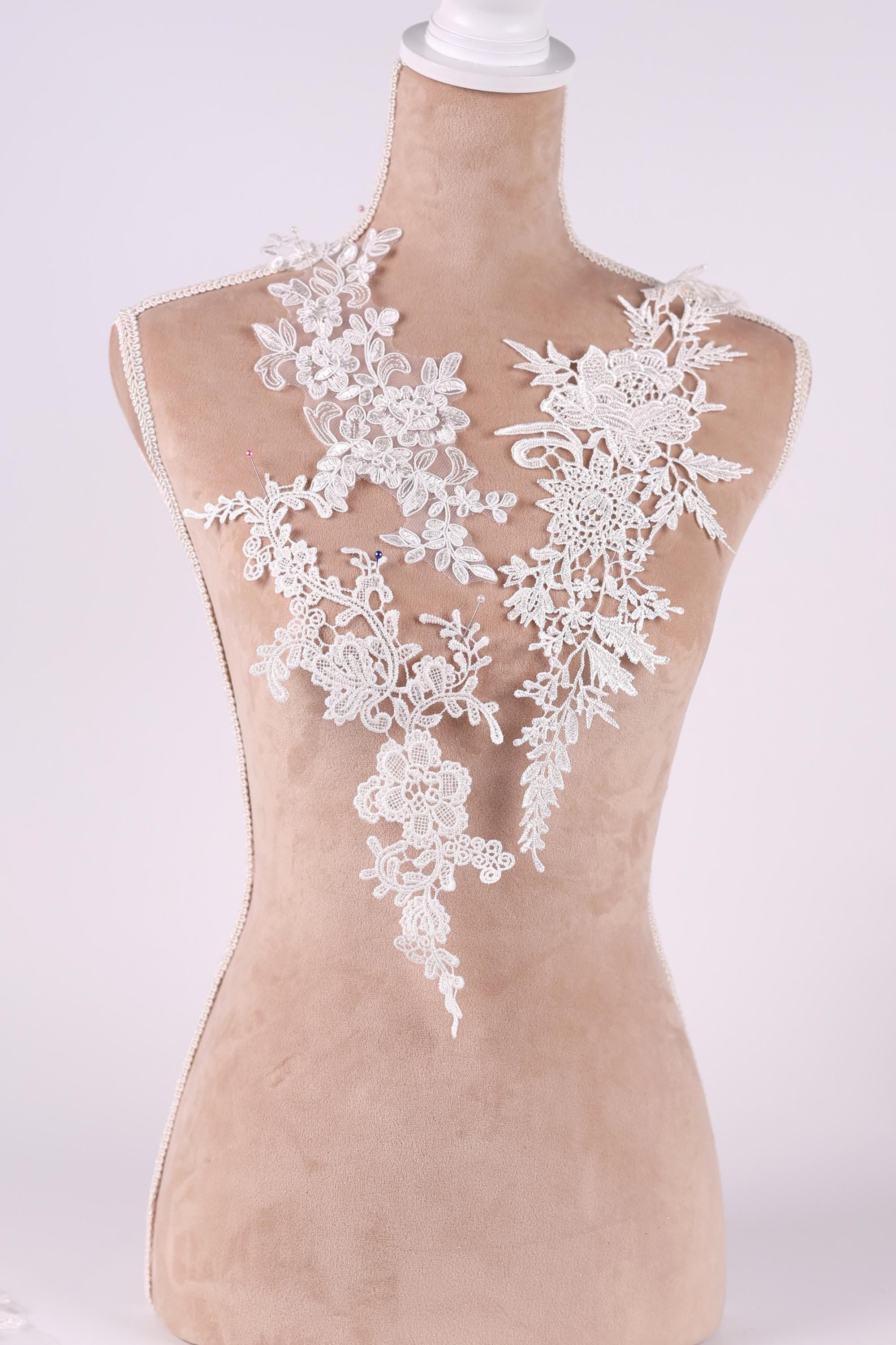 A mannequin wearing a white lace dress with intricate floral patterns.