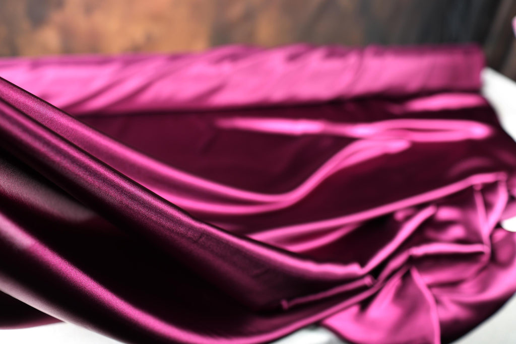 a close up of a purple cloth on a bed