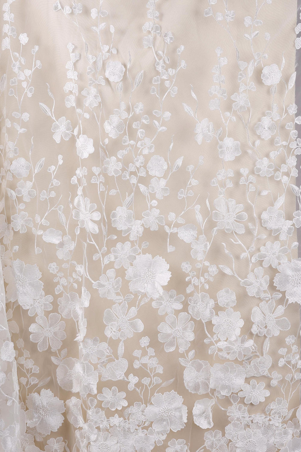 a close-up view of a delicate, white lace fabric with a floral pattern. The lace appears to be made of a soft, delicate material, possibly silk or chiffon, and is adorned with numerous small white flowers and leaves, creating a beautiful and intricate design. The fabric is spread out, allowing for a clear view of its texture and pattern.