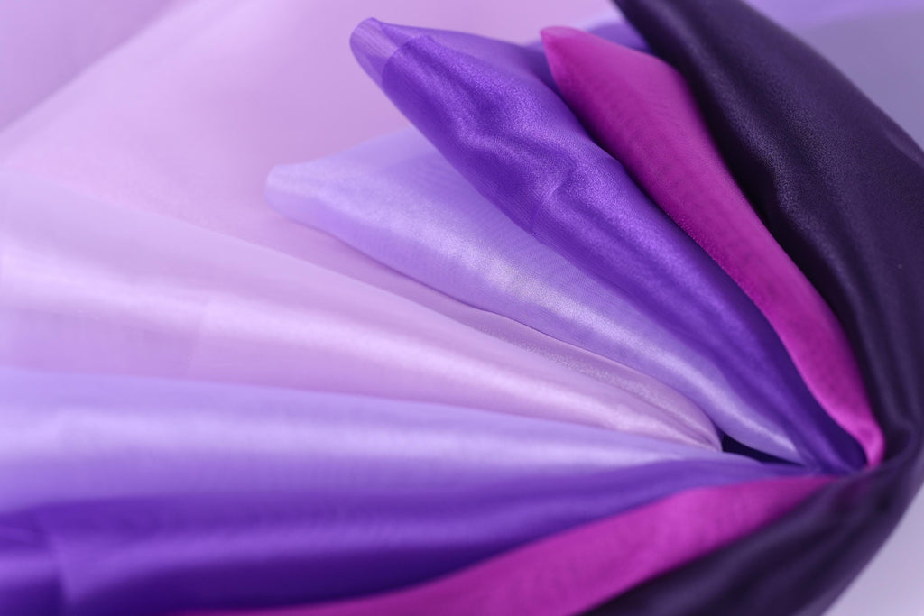 a close-up view of a variety of colorful fabrics, including purple, pink, and white, arranged in a visually appealing manner.