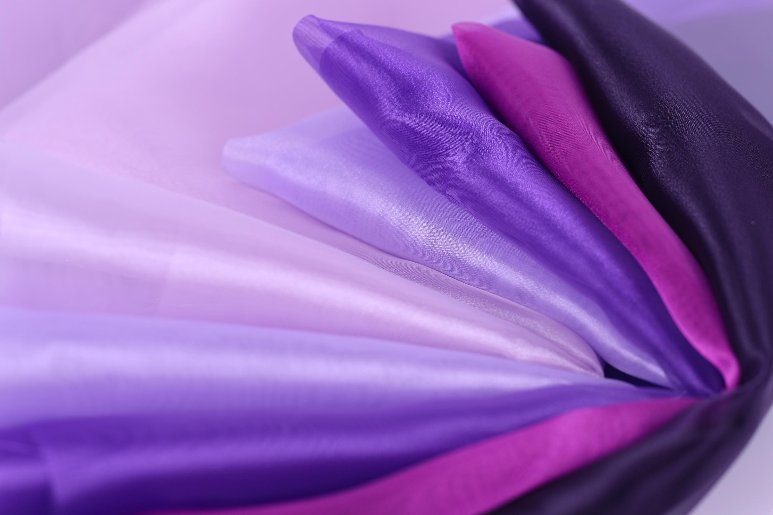 a close-up view of a variety of colorful fabrics, including purple, pink, and white, arranged in a visually appealing manner.