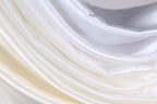The image is a close-up of a soft, flowing fabric with a gradient of white and yellow colors. The fabric appears to be made of silk or satin, and it has a smooth, shiny texture. The colors are vibrant and the fabric is draped in a way that creates a sense of movement and softness.