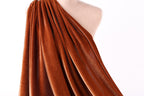 a close-up view of a piece of orange velvet fabric draped over a mannequin torso.