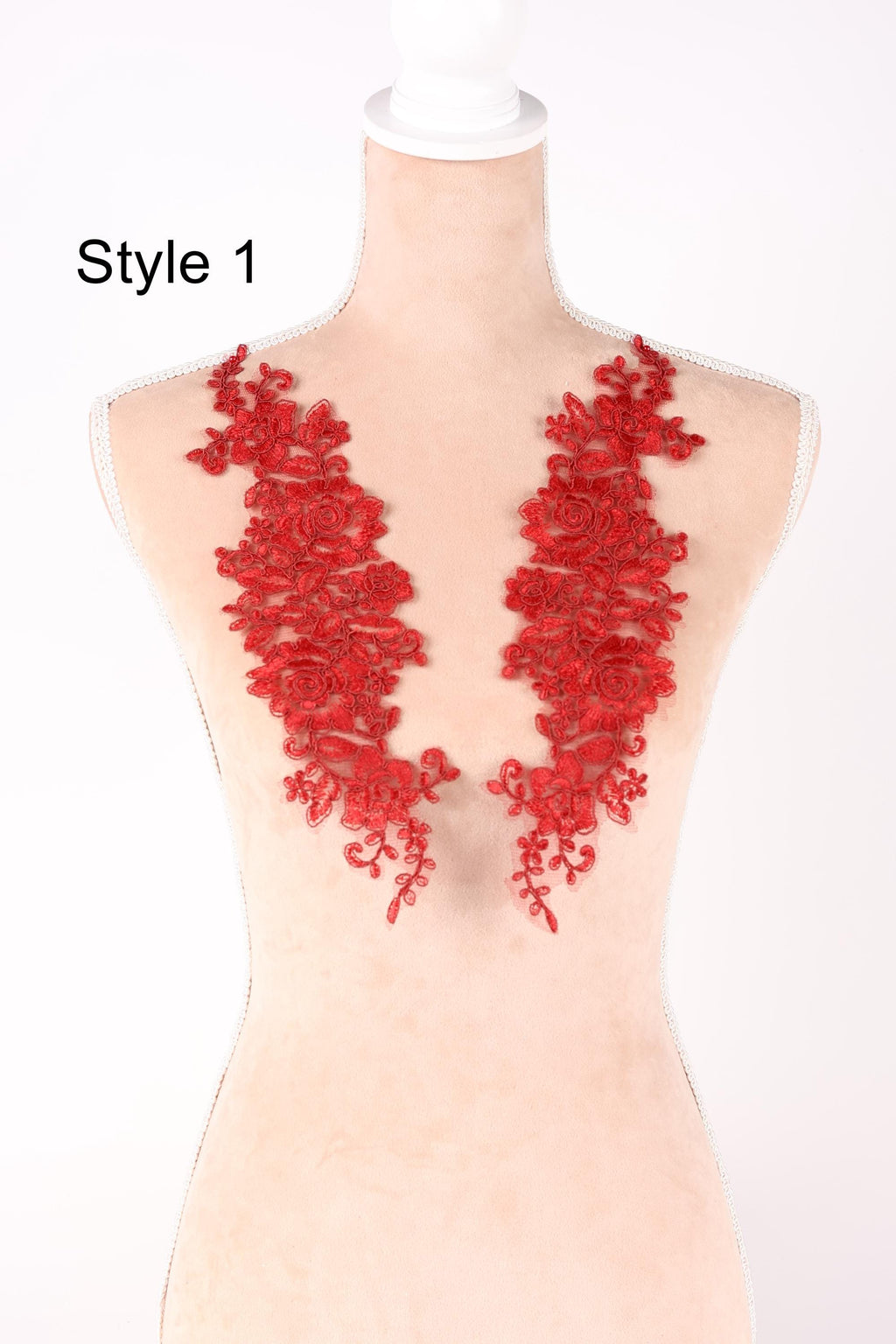 A mannequin wearing a red lace dress with a floral pattern on the shoulders.
