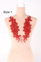 A mannequin wearing a red lace dress with a floral pattern on the shoulders.
