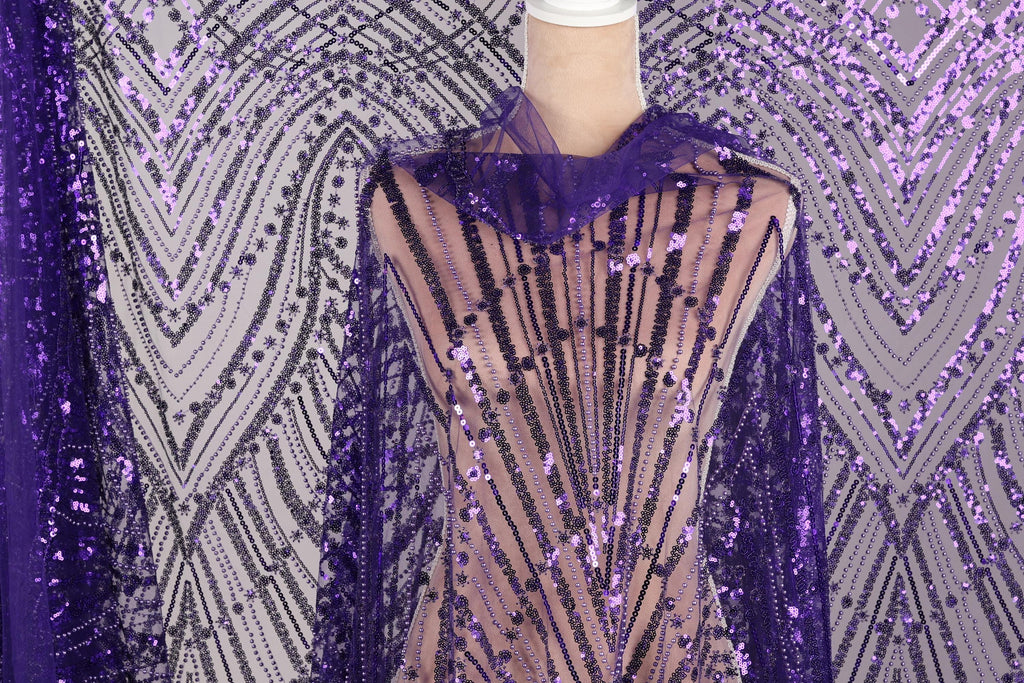 a mannequin wearing a purple sequin fabric with a sheer overlay. The fabric has a pattern of purple and black sequins, creating a visually striking and eye-catching design.