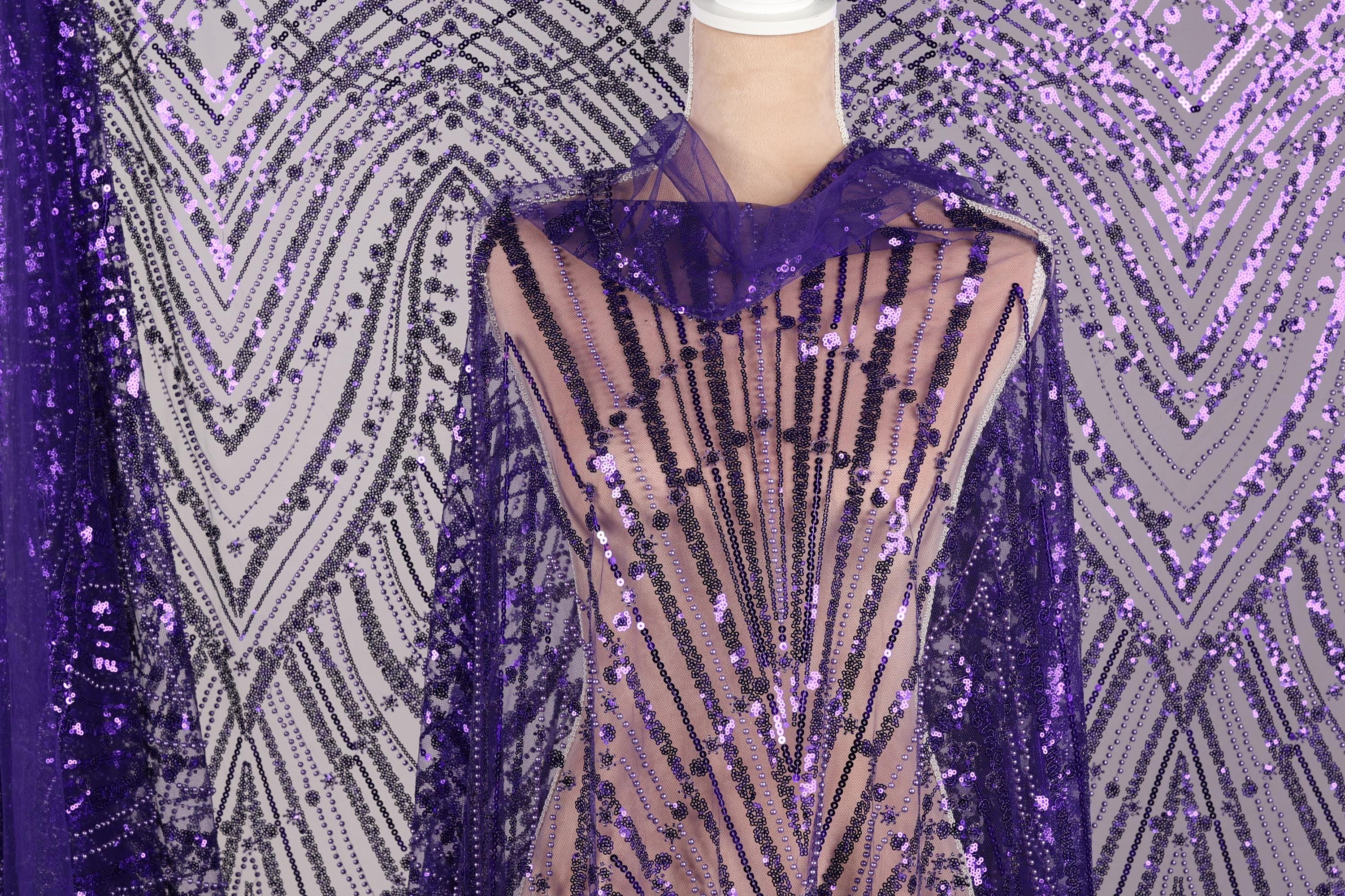 a mannequin wearing a purple sequin fabric with a sheer overlay. The fabric has a pattern of purple and black sequins, creating a visually striking and eye-catching design.
