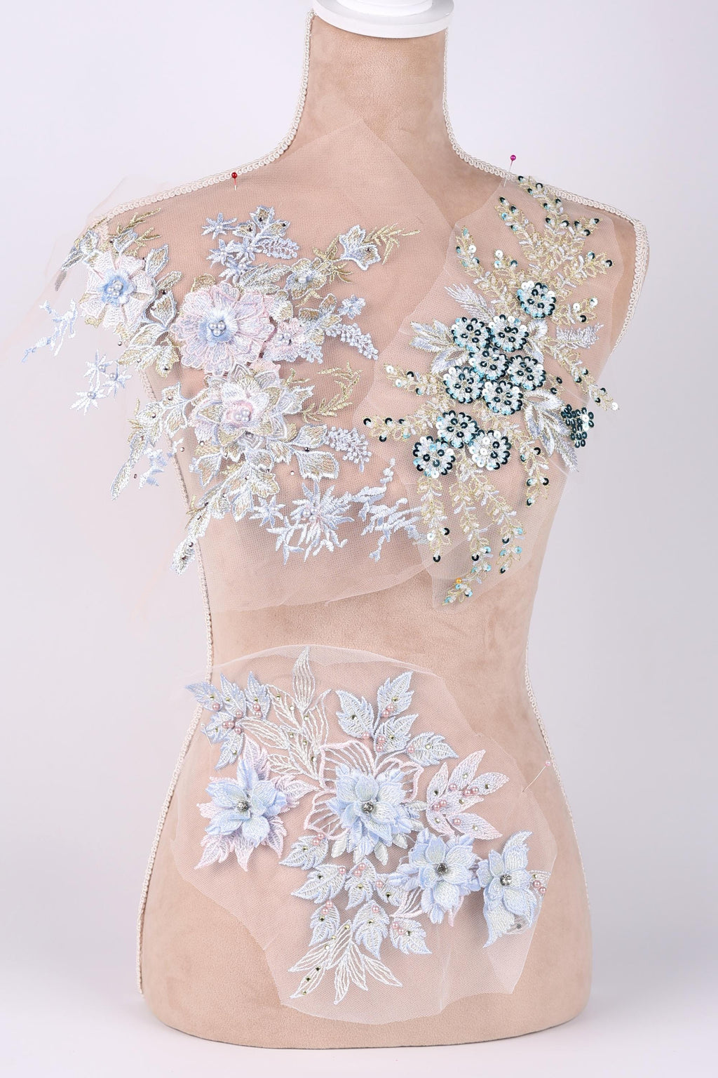 A mannequin with a beige body and a white bust form, adorned with intricate floral and leaf designs in shades of blue and white.