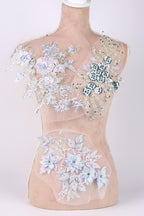 A mannequin with a beige body and a white bust form, adorned with intricate floral and leaf designs in shades of blue and white.