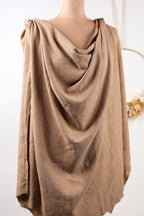 A mannequin wearing a beige, draped garment with a flowing, draped appearance.