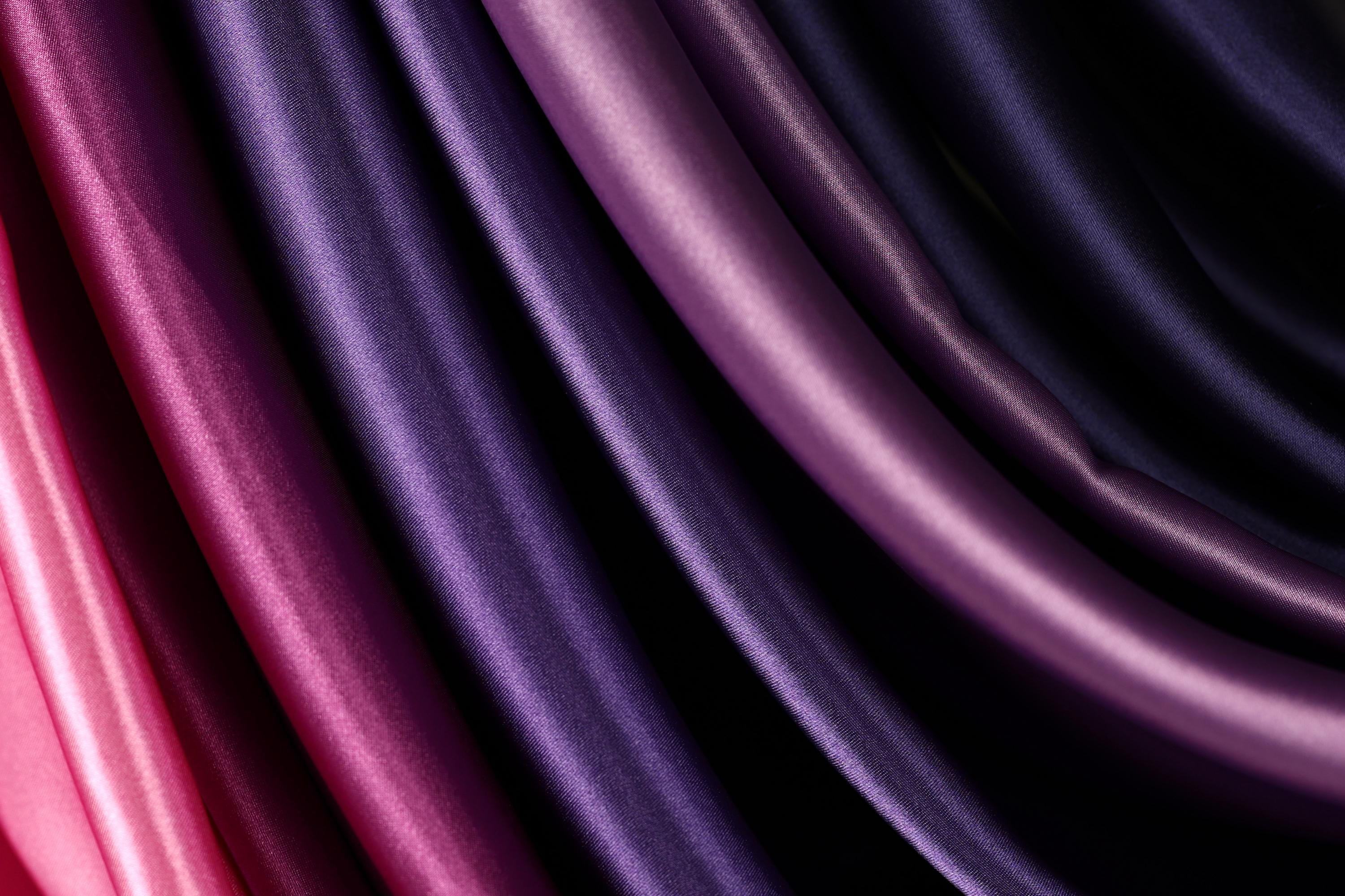 a close-up view of a variety of colorful fabrics, including shades of purple, pink, and black.