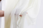 A hand is holding a white fabric, possibly a curtain or a sheet, with the fabric partially pulled back.
