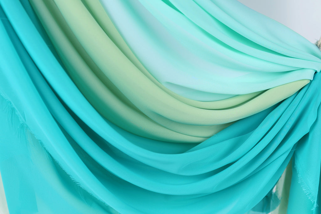 a close-up view of a collection of turquoise and mint-colored fabric swatches, creating a visually appealing gradient effect.