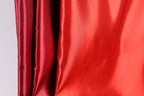 a close-up view of a red fabric, with a blurred red fabric visible in the background.