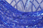 The image is a close-up of a fabric with a blue sequin pattern, featuring a repeating diagonal line design.