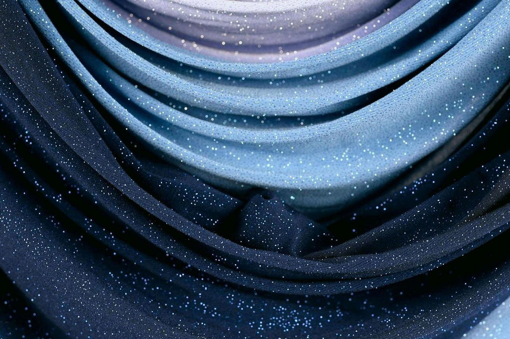 a close-up view of a fabric with a blue and purple color scheme, adorned with small white specks or glitter. The fabric appears to be folded or draped, creating a sense of depth and texture. The overall composition is visually striking and captures the viewer's attention.