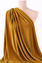 A mannequin wearing a gold velvet fabric draped over its body.