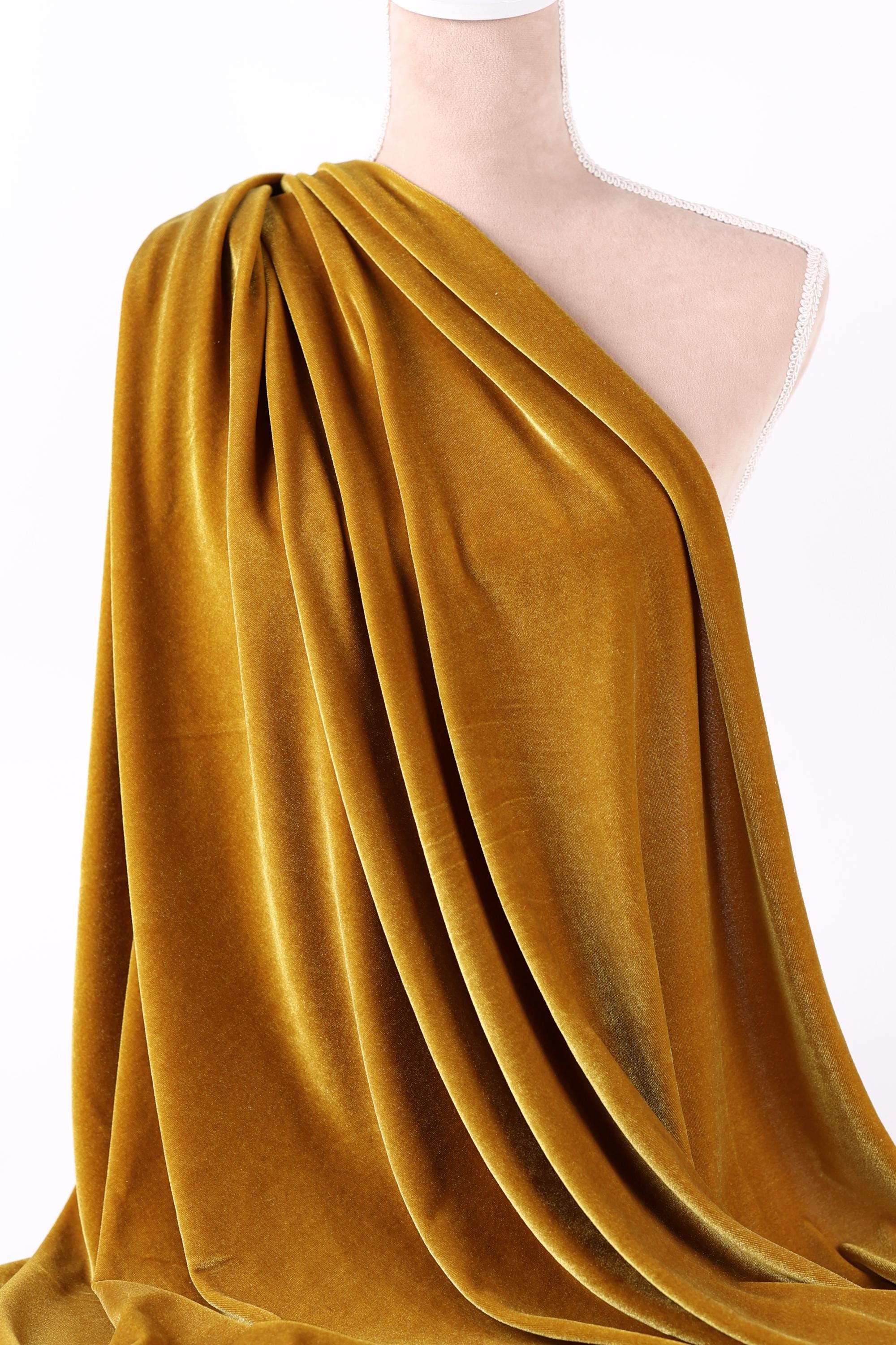 A mannequin wearing a gold velvet fabric draped over its body.