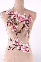 A mannequin torso with a floral embroidered design on it, featuring pink and white flowers and branches.
