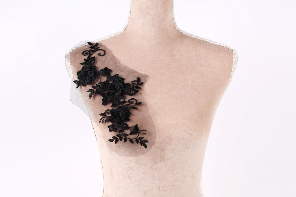 A mannequin with a decorative black lace piece on its shoulder.