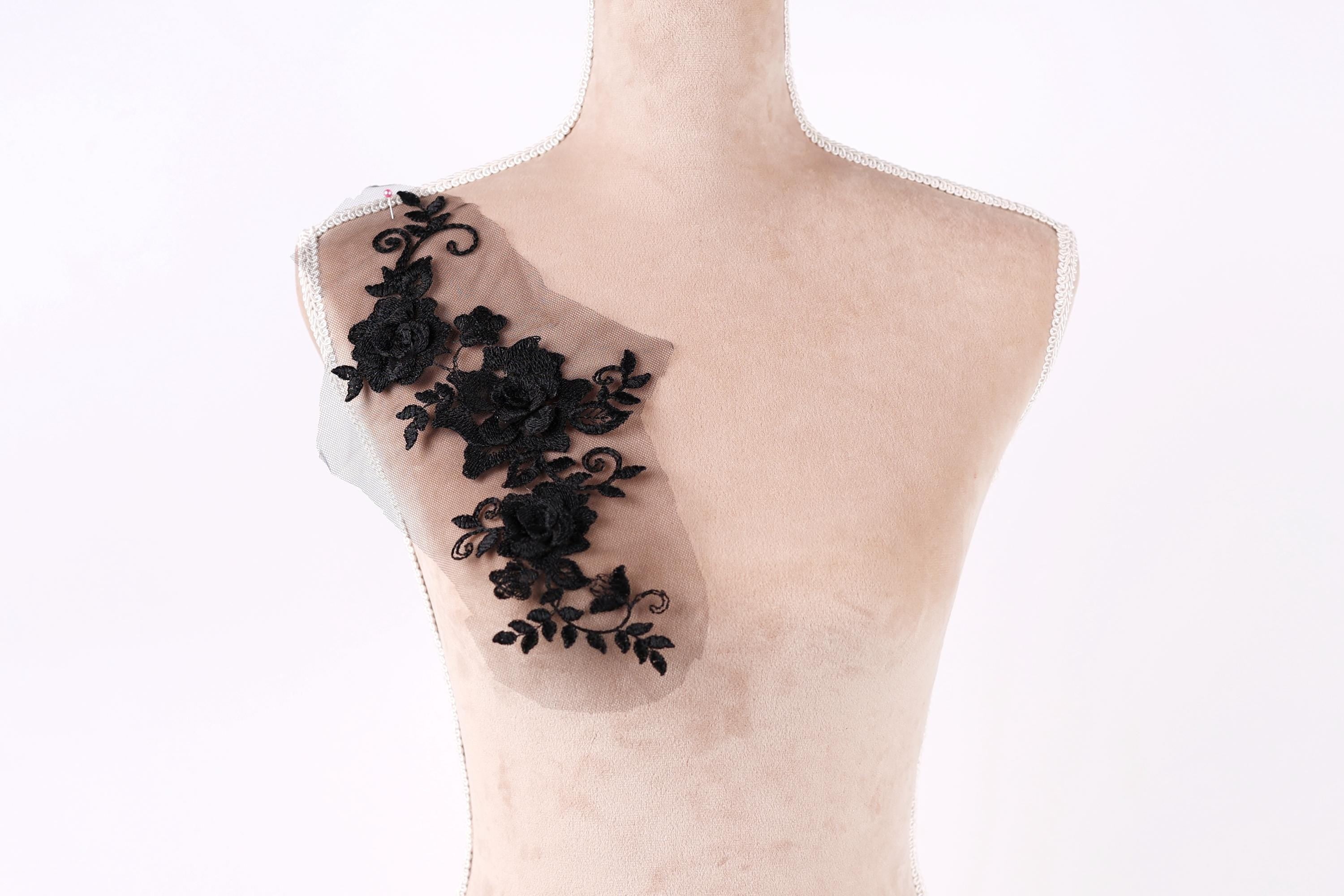 A mannequin with a decorative black lace piece on its shoulder.