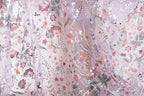 The image is a close-up view of a delicate, intricately embroidered fabric with a floral pattern. The fabric appears to be made of sheer material, giving it a soft and delicate appearance. The embroidered flowers and leaves are arranged in a way that creates a visually appealing and intricate design.