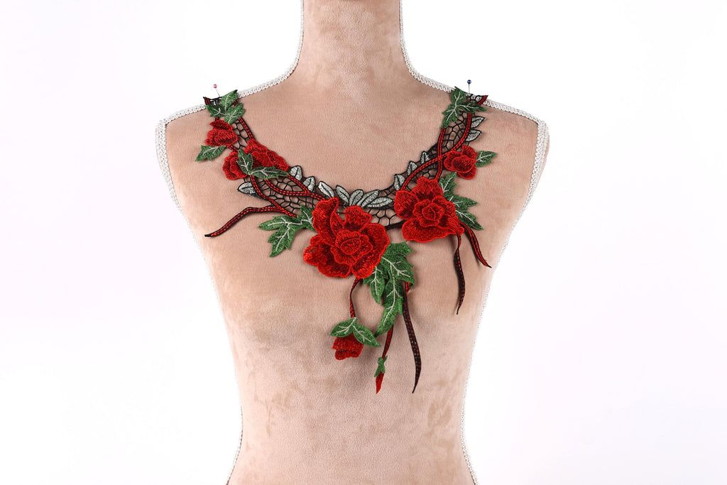 A mannequin wearing a necklace with red roses and green leaves.