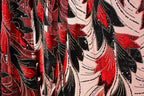 a close-up view of a fabric with a striking pattern of red, black, and white sequins and beads. The pattern is intricate and detailed, with the sequins and beads creating a visually captivating design. The fabric appears to be a sheer material, which adds to the overall aesthetic of the image.