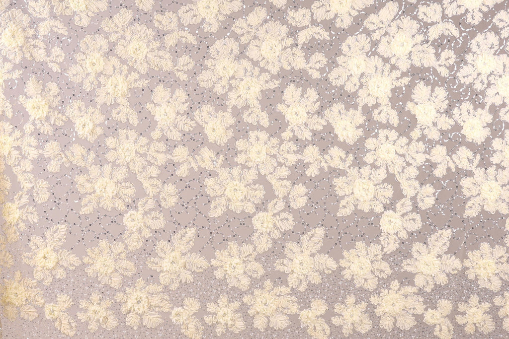 a close-up view of a fabric with a floral pattern. The fabric appears to be made of a light-colored material, possibly lace or a similar type of material. The pattern consists of numerous small white flowers or leaves scattered across the fabric, creating a visually appealing and intricate design.