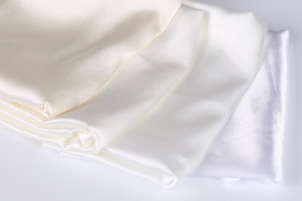 a close-up view of three white fabric pieces, possibly silk or satin, arranged in a horizontal line.