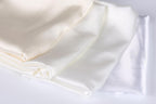 a close-up view of three white fabric pieces, possibly silk or satin, arranged in a horizontal line.