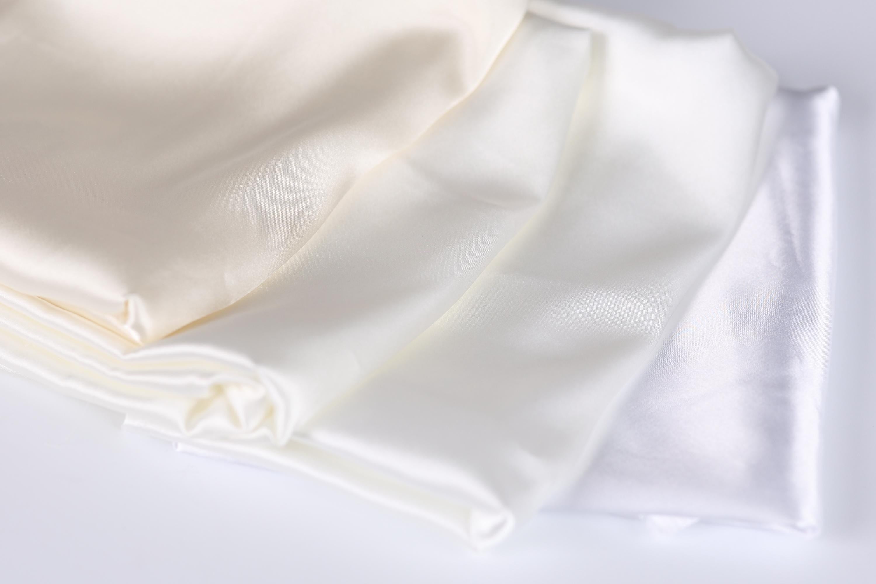 a close-up view of three white fabric pieces, possibly silk or satin, arranged in a horizontal line.