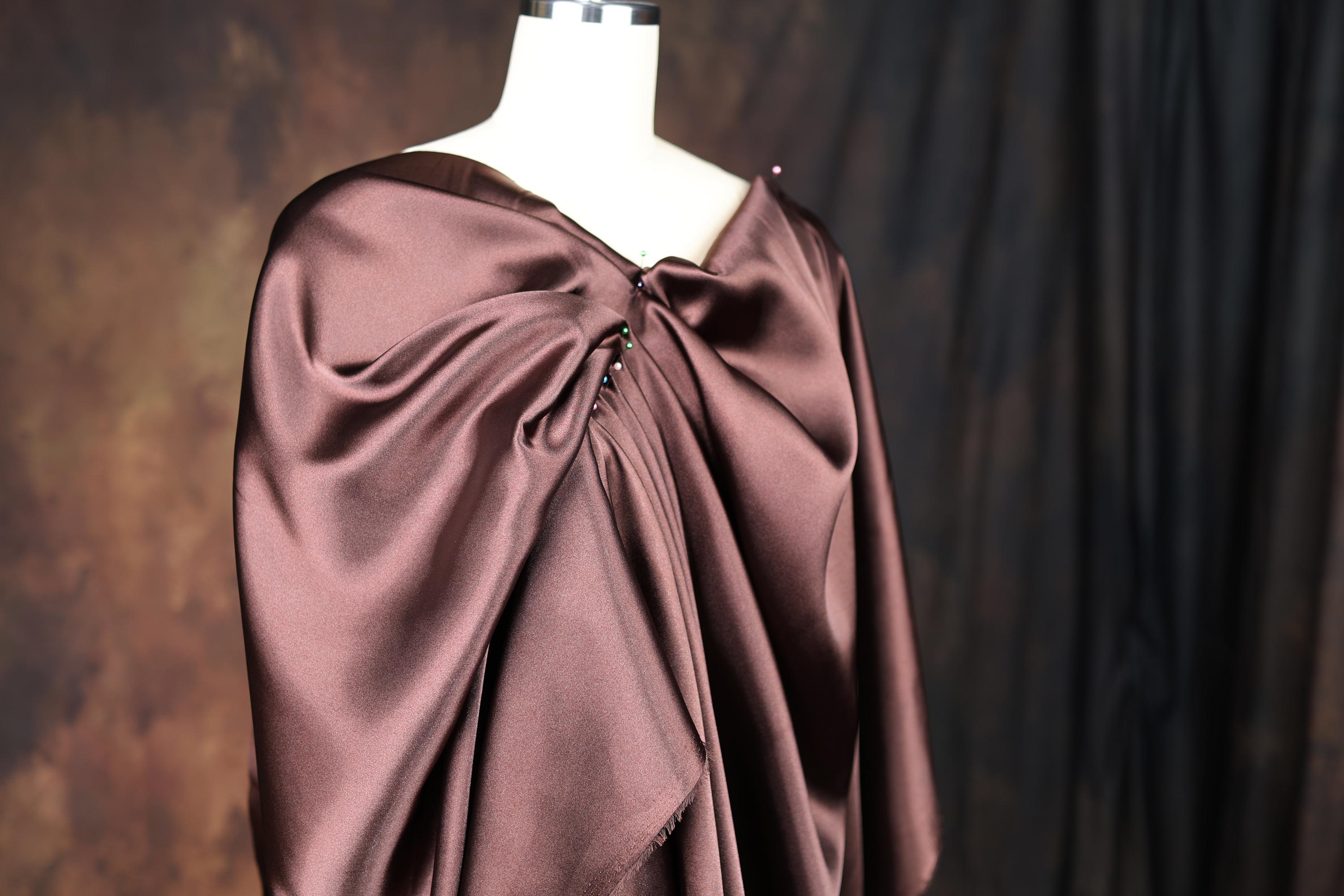 a dress on a mannequin with a brown cape