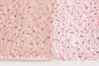 two fabric pieces with a floral pattern. The left fabric piece is a light pink fabric with a delicate, leaf-like design, while the right fabric piece is a white fabric with a similar floral pattern.