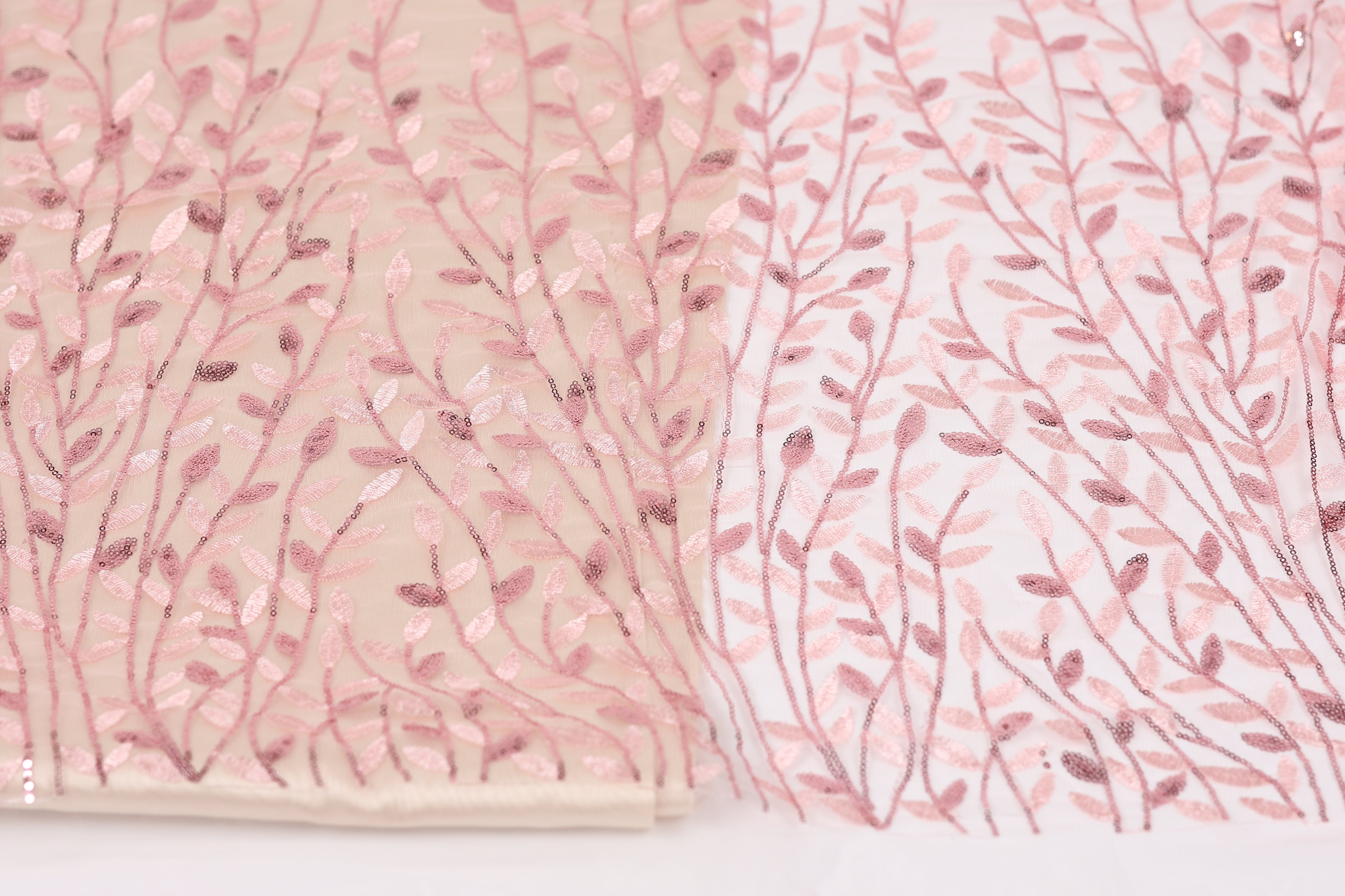 two fabric pieces with a floral pattern. The left fabric piece is a light pink fabric with a delicate, leaf-like design, while the right fabric piece is a white fabric with a similar floral pattern.