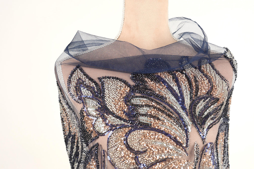 A mannequin wearing a dress with a sheer, sequined bodice and a blue, sheer, floral-patterned collar.