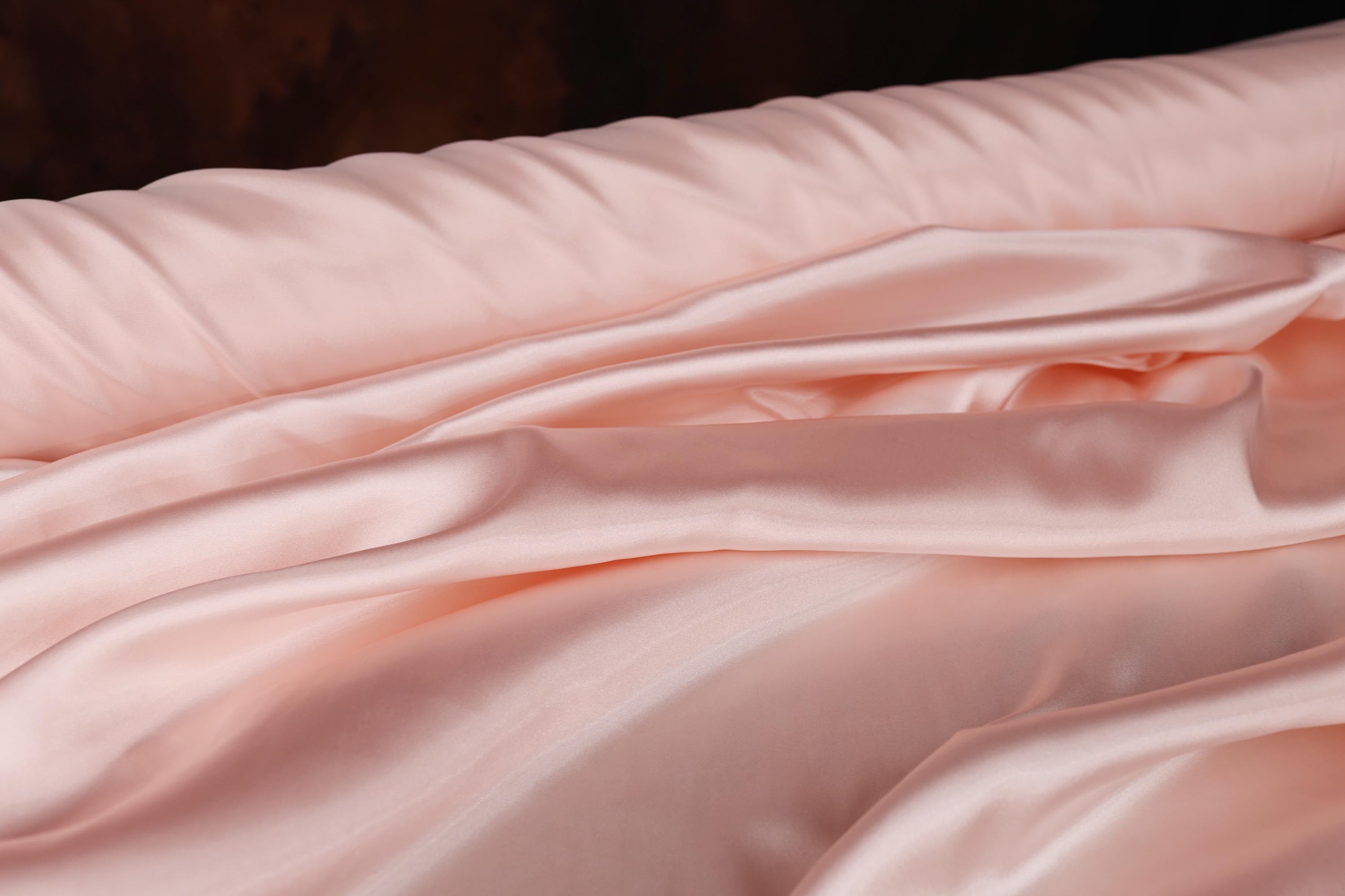 a close up of a bed with a pink comforter
