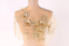 A mannequin with a sheer, golden-colored fabric draped over its back, adorned with intricate floral embroidery.